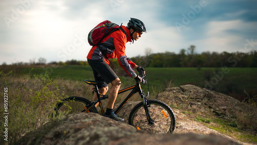 Cyclist in Red Riding the Bike on the Rocky Trail at Evening. Extreme Sport and Enduro Biking Concept.