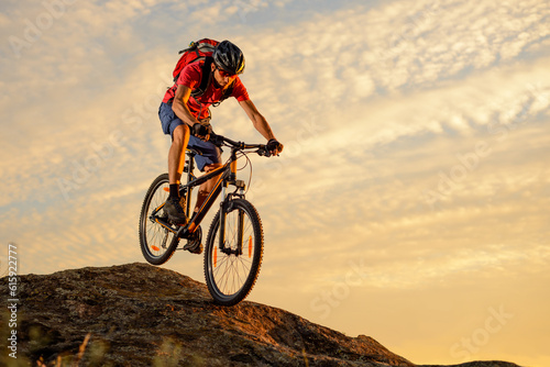 Cyclist in Red T-Shirt Riding the Bike Down the Rock on the Sunset Sky Background. Extreme Sport and Enduro Biking Concept.