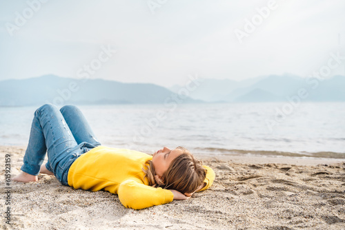 Lonely beautiful sad girl teenager lying thoughtfully on sand sea beach. Dreams,anxiety,worries about future,school friends,parents. Teen bullying, psychological problems in adolescent puberty period