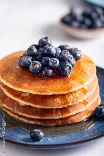 Fresh American Pancakes with blueberries and maple syrup on blue plate