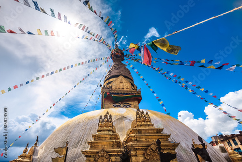 Nepal. Golden Stupa Bouddanath in Kathmandu with colorful Tibetan prayer flags, close-up on a sunny day. Was built in the 14th century. Blue cloudy sky in the background. Travel, holidays, sight photo