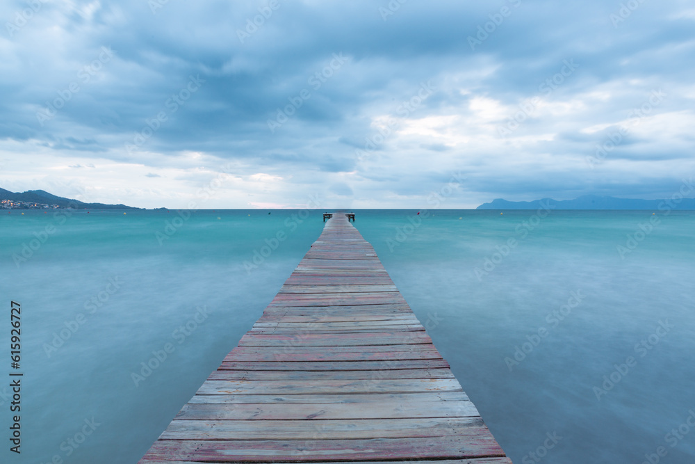 Dramatic Looking Morning at the Sea in Spain - Majorca. Blue Hour with Clouds on the Wooden Pier / Jetty