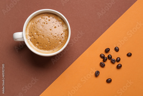 Cup of hot espresso and coffee beans on color background