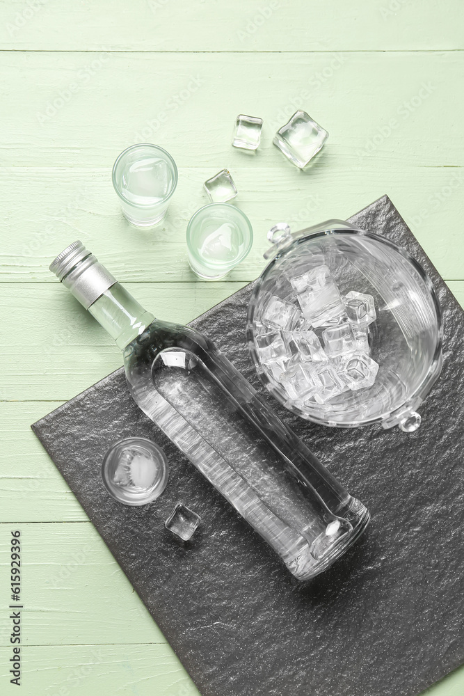 Bottle and glasses of cold vodka on green wooden background Bottle and glasses of cold vodka on green wooden background