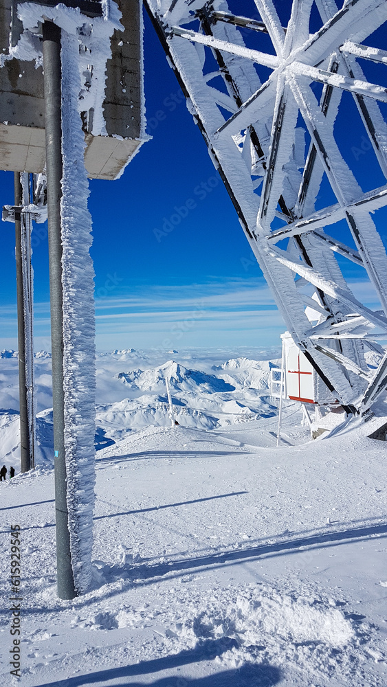 Frozen top station of a large gondola in the French ski resort Les Trois Vallees with a sunny blue sky and the white snow-covered mountain peaks of the Alps in the background Frozen top station of a large gondola in the French ski resort Les Trois Vallees with a sunny blue sky and the white snow-covered mountain peaks of the Alps in the background
