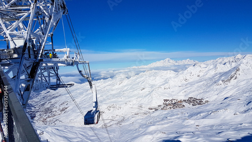 Frozen top station of a large gondola in the French ski resort Les Trois Vallees with a sunny blue sky and the white snow-covered mountain peaks of the Alps in the background photo