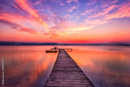 Exciting sunset at shore with wooden pier and boat