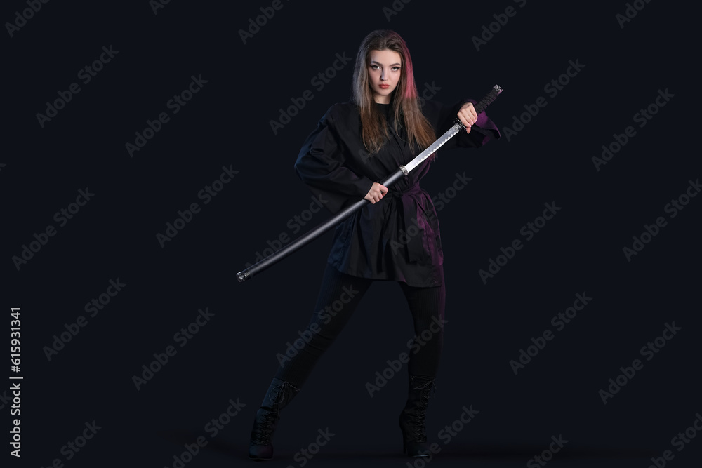 Beautiful young woman with katana on dark background Beautiful young woman with katana on dark background