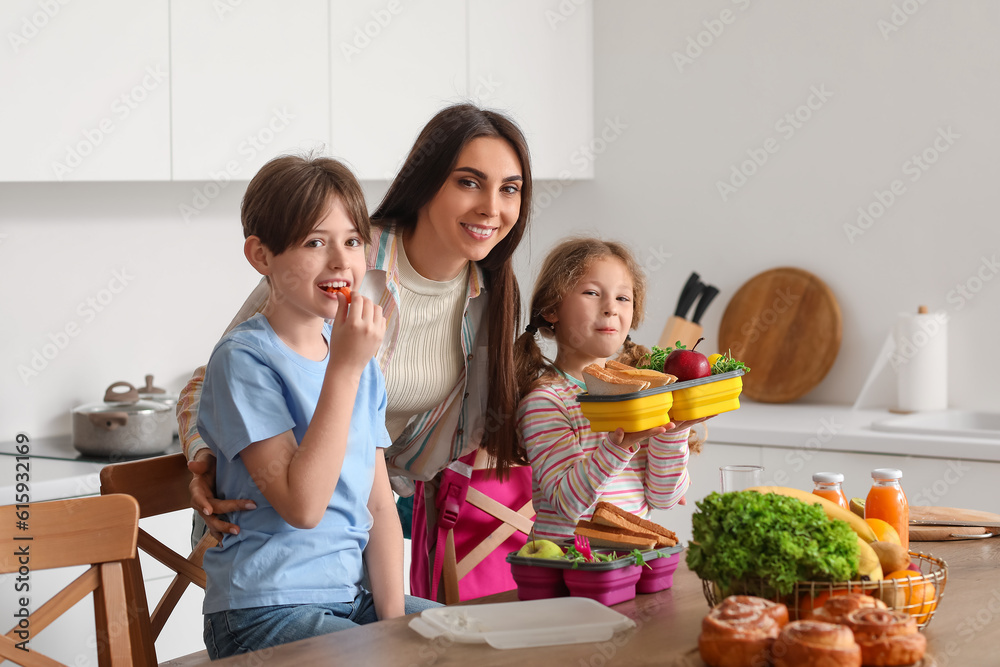 Mother packing school lunch for her little children in kitchen