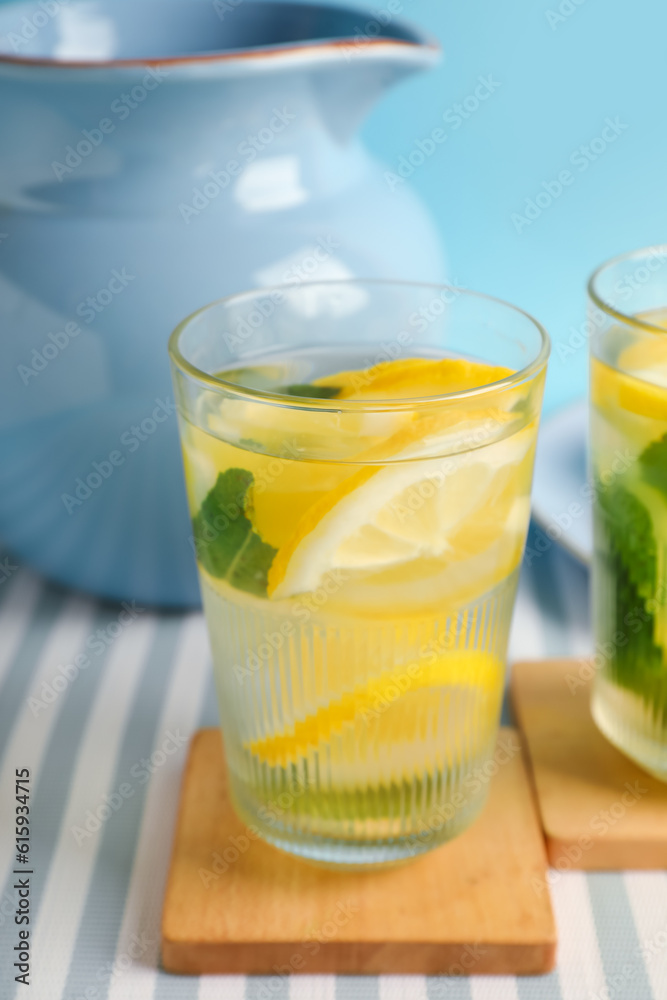 Fototapeta premium Glasses and jug of infused water with lemon and mint on blue background