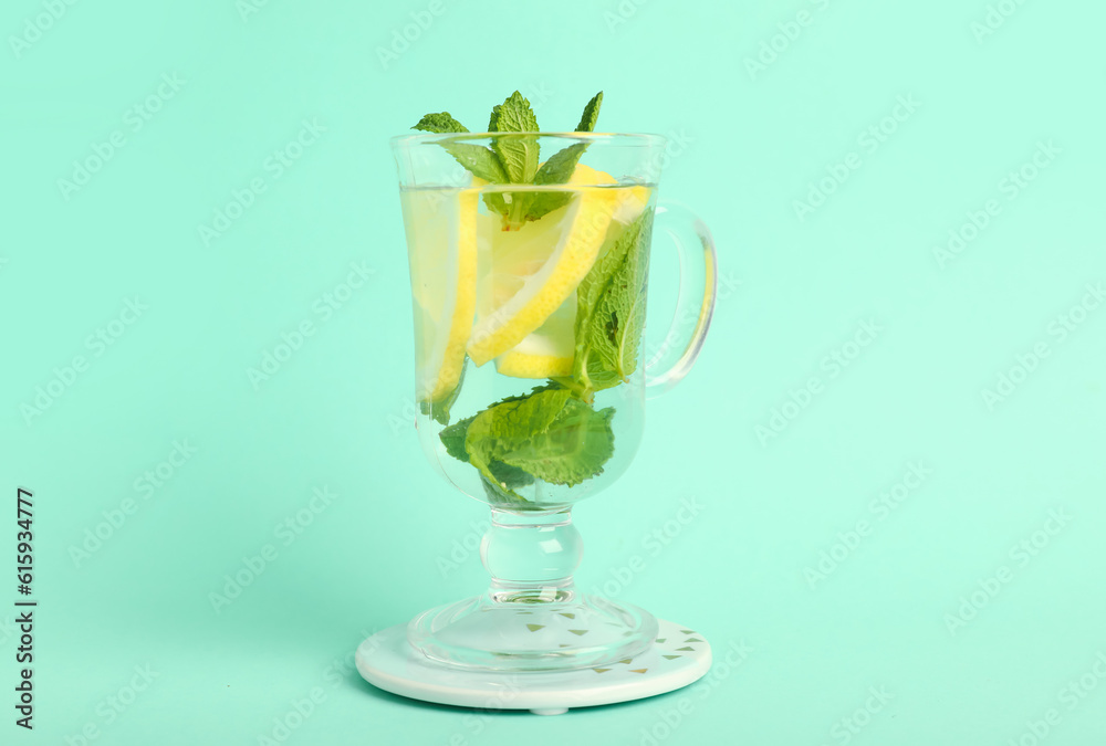 Glass of infused water with lemon and mint on turquoise background Glass of infused water with lemon and mint on turquoise background
