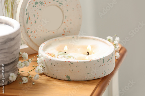 Gypsophila flowers and burning candle on table in room  closeup