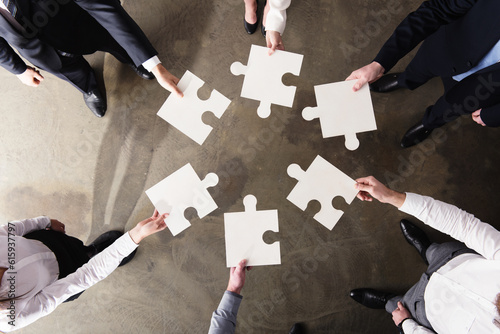 Businessmen working together to build a big puzzle. Concept of teamwork, partnership, integration and startup.