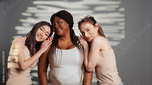 Group of multiracial women smiling for body positivity ad, curvy and skinny friends advertising femininity and body confidence. Girls with different skintones and body types in studio.