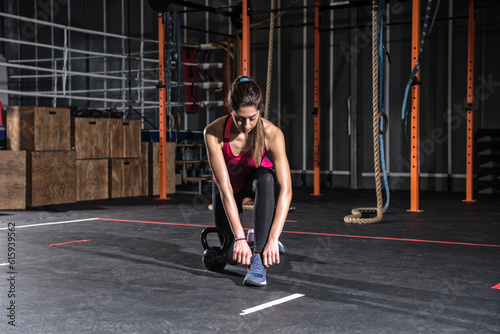Determined athletic girl ready to start exercises with a kettlebell at the gym