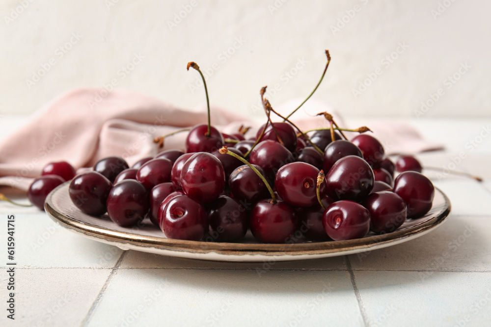 Plate with sweet cherries on white tile table Plate with sweet cherries on white tile table