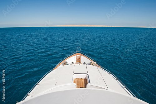 View over the bow of a large luxury motor yacht on tropical open ocean with sun beds