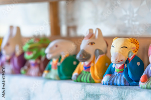 Ceramic made figurines of the twelve japanese zodiac signs or juunishi depicted as fun animals of the sexagenary cycle and focusing to the sheep wearing a colorful traditional crested hakama kimono.