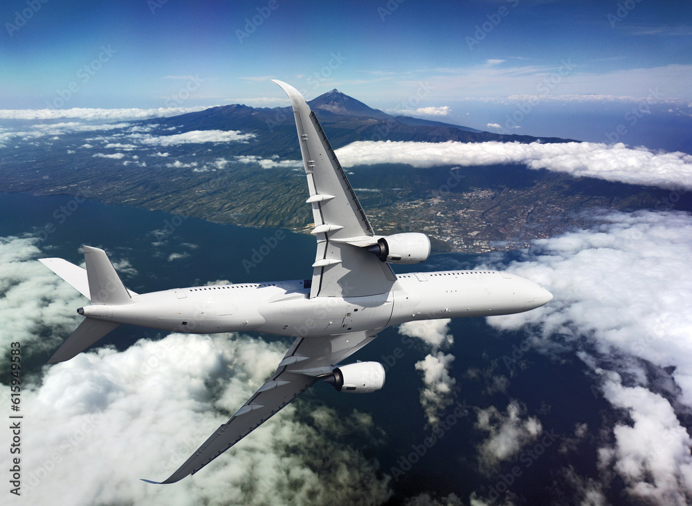 Fototapeta premium Airplane flying over the island and mountains with a clouds
