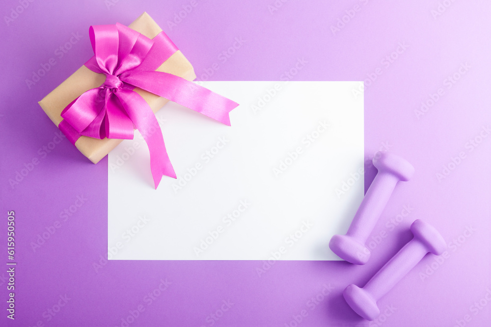 Holiday birthday party sport flat lay composition with purple dumbbells and craft gifts with lilac bow on violet paper background. Top view, horizontal orientation Holiday birthday party sport flat lay composition with purple dumbbells and craft gifts with lilac bow on violet paper background. Top view, horizontal orientation