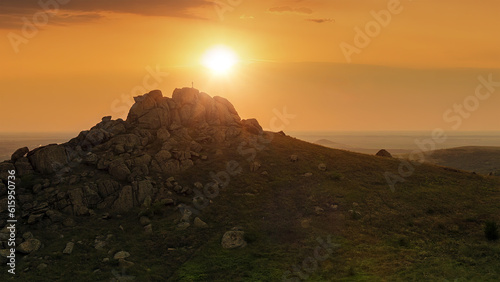Silhouette of a cross on mountain top at sunrise