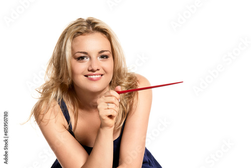 Studio portrait of beautiful young woman smiling to the camera and pointing towards something. Isolated on white background.