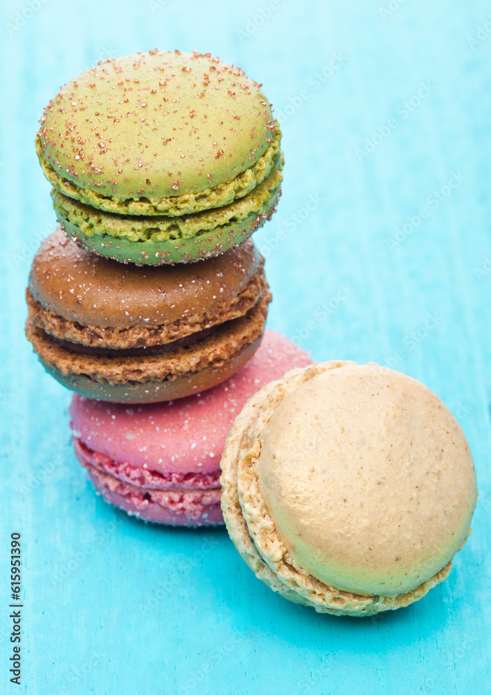 French luxury colorful macarons dessert cakes on blue wood background with sugar on top