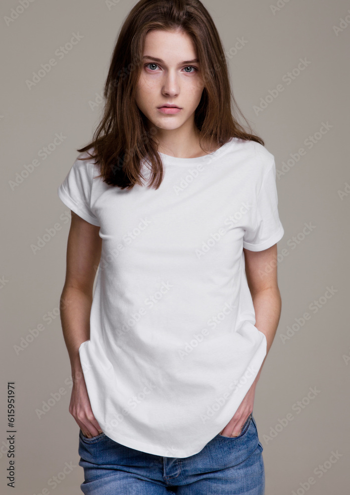 Model test portrait with young beautiful fashion model posing on grey background. Wearing white t-shirt and jeans. Model test portrait with young beautiful fashion model posing on grey background. Wearing white t-shirt and jeans.