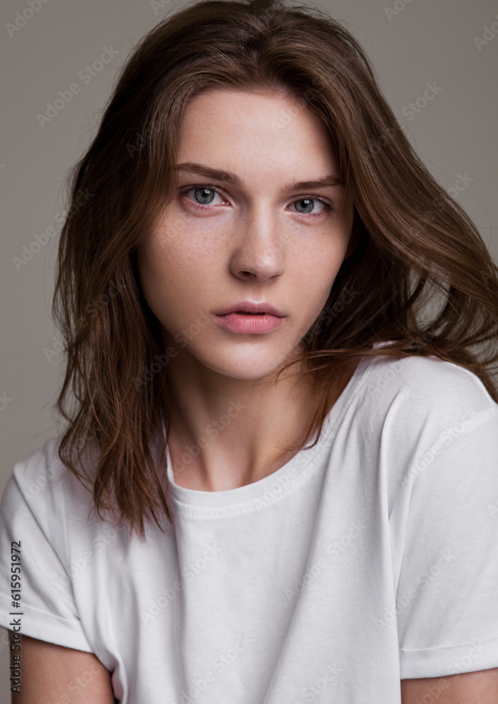Model test portrait with young beautiful fashion model posing on grey background. Wearing white t-shirt. Classic portrait. Model test portrait with young beautiful fashion model posing on grey background. Wearing white t-shirt. Classic portrait.