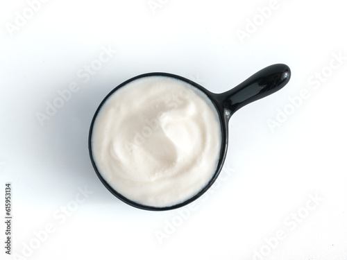Beautiful greek yogurt or sour cream in black bowl, isolated on white background with clipping path. Top view or flat-lay.
