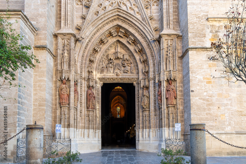 The ornate doorway and facade of the Cathedral of Saint Mary of the See, the largest Gothic cathedral in the world, in the Barrio Santa Cruz district of the Andalucian city of Seville, Spain.