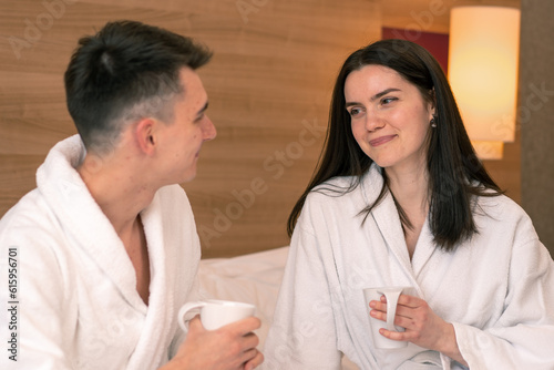 young couple on honeymoon in hotel room having breakfast in room drinking coffee happy lovers travel concept