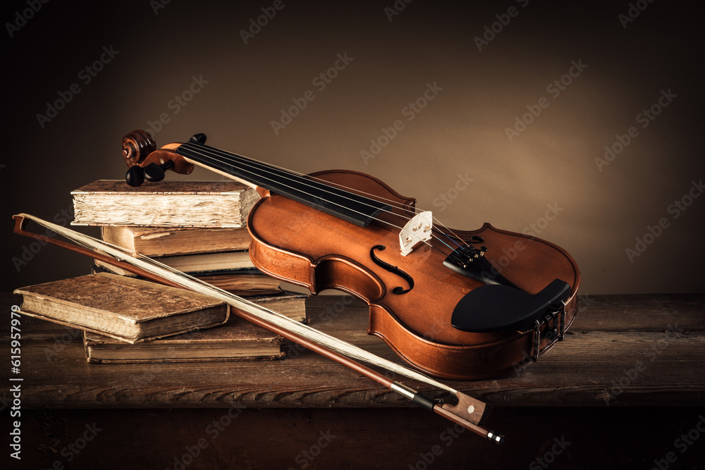 Fototapeta premium Violin, bow and old books on a rustic wooden table, arts and music concept