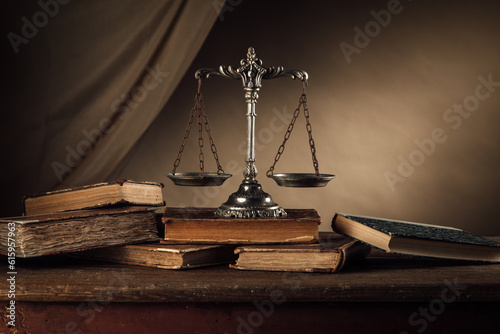 Old silver scale and hardcover books on a wooden table, justice and knowledge concept