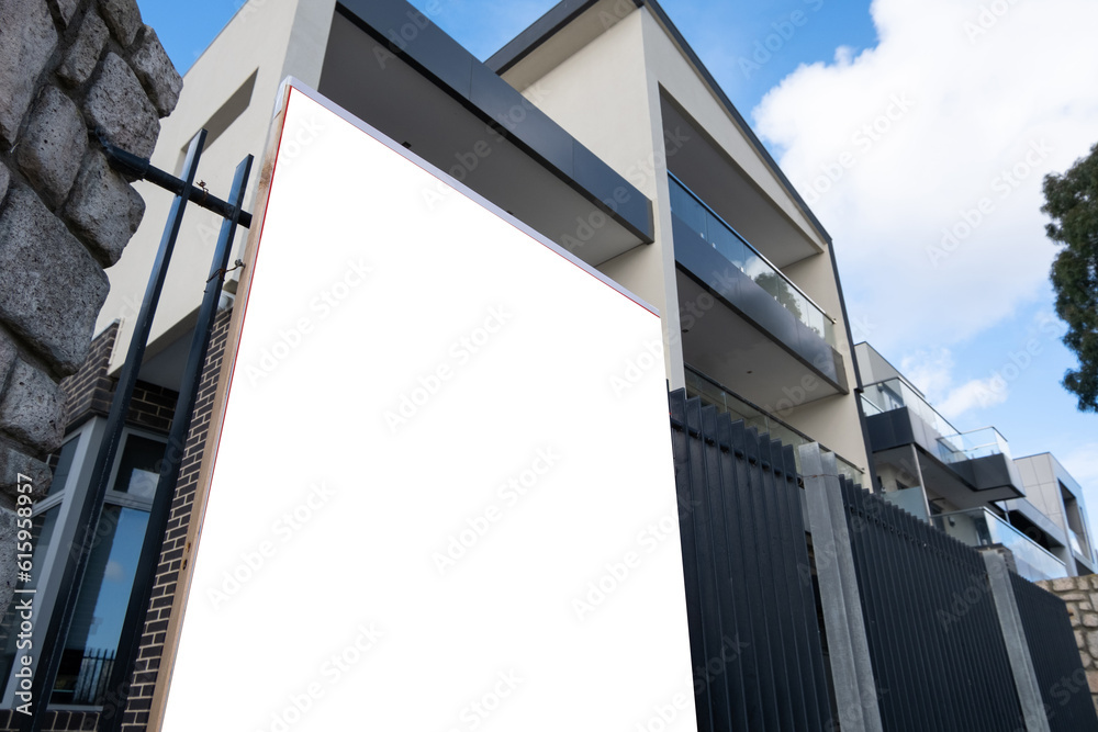 Blank white mockup template of a real estate sign board on fence with a modern multi-storey Australian luxury home at the back. Background texture of advertising panel with copy space for your text. Blank white mockup template of a real estate sign board on fence with a modern multi-storey Australian luxury home at the back. Background texture of advertising panel with copy space for your text.