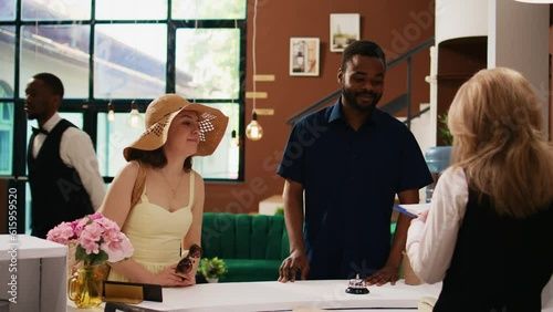 Guests filling in registration papers at reception, doing check in procedure with front desk staff at tropical hotel. Travellers on honeymoon registering at luxury resort. Handheld shot. photo