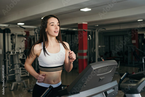 Young pretty girl is trained in the gym. Running on a treadmill in the gym