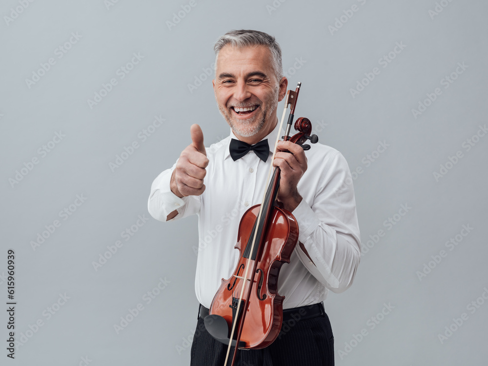 Cheerful violinist posing with a violin and giving a thumbs up Cheerful violinist posing with a violin and giving a thumbs up
