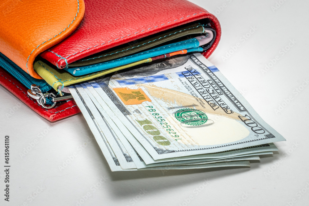 Several new design 100 US dollar bills in a colored wallet, on a white background. Cash banknotes of 100 dollars. The concept of wealth, business, finance, bank, currency, economy Several new design 100 US dollar bills in a colored wallet, on a white background. Cash banknotes of 100 dollars. The concept of wealth, business, finance, bank, currency, economy