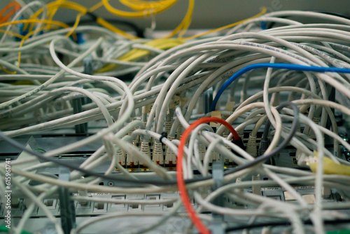 a bunch of patch network cables sorted in a rack cabinet leading from a patch panel in a server rack in a data center room internet cloud storage