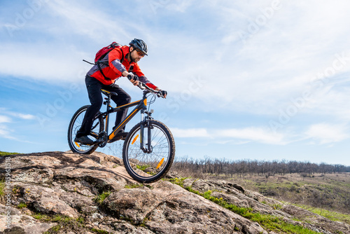 Cyclist in Red Jacket Riding the Mountain Bike Down Rocky Hill. Extreme Sport and Adventure Concept. © Designpics
