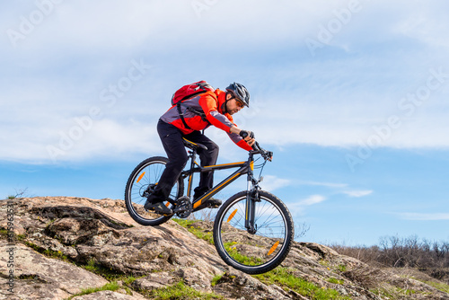 Fototapeta Naklejka Na Ścianę i Meble -  Cyclist in Red Jacket Riding the Mountain Bike Down Rocky Hill. Extreme Sport and Adventure Concept.