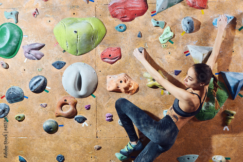 Workout exercise. back view of woman climber climbs indoors in bouldering gym with dramatic light