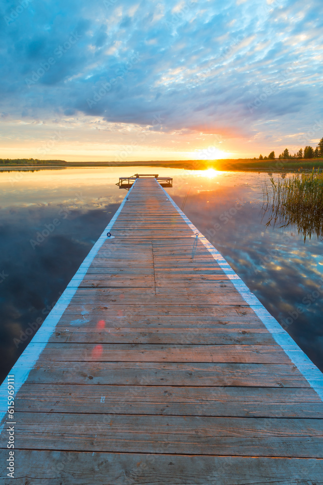 vertical photo of a beautiful landscape - a long wooden pier and a setting sun over a picturesque lake vertical photo of a beautiful landscape - a long wooden pier and a setting sun over a picturesque lake
