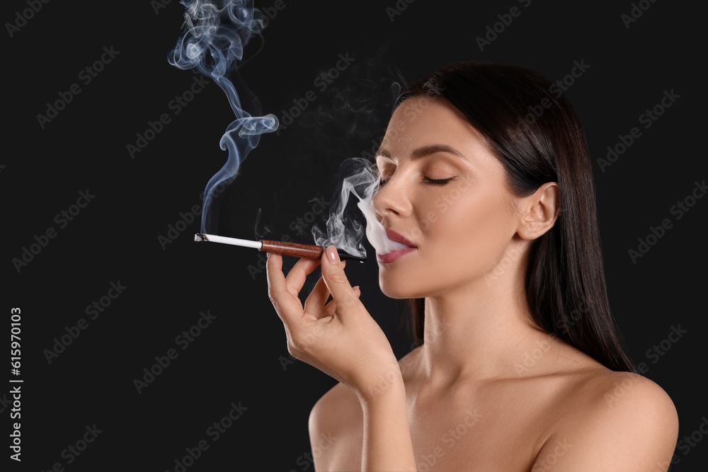 Obraz premium Woman using long cigarette holder for smoking on black background, space for text