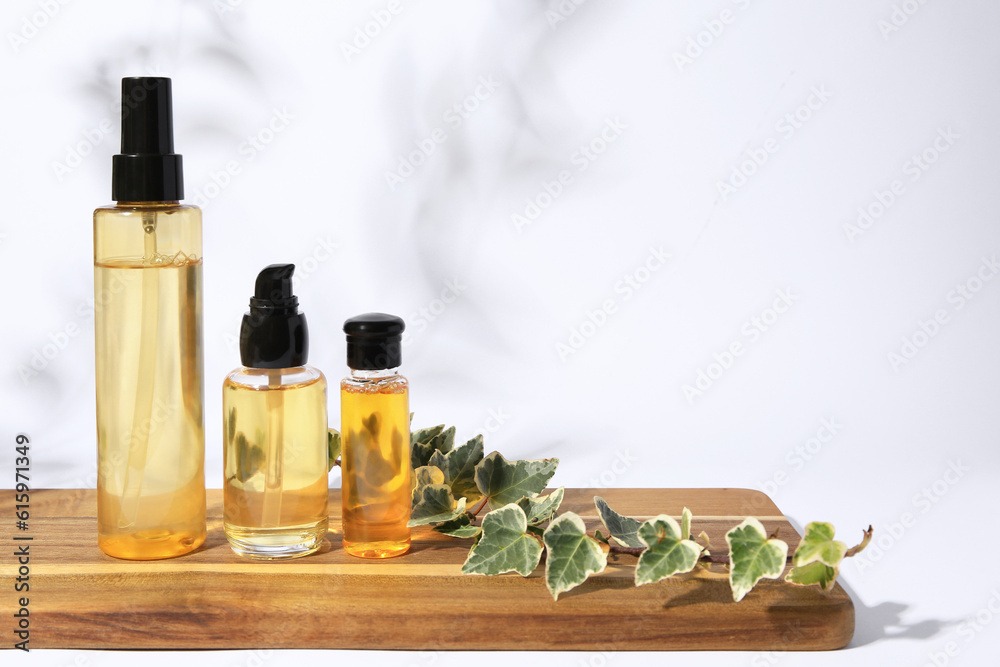 Bottles with cosmetic products and ivy leaves on white background. Space for text Bottles with cosmetic products and ivy leaves on white background. Space for text