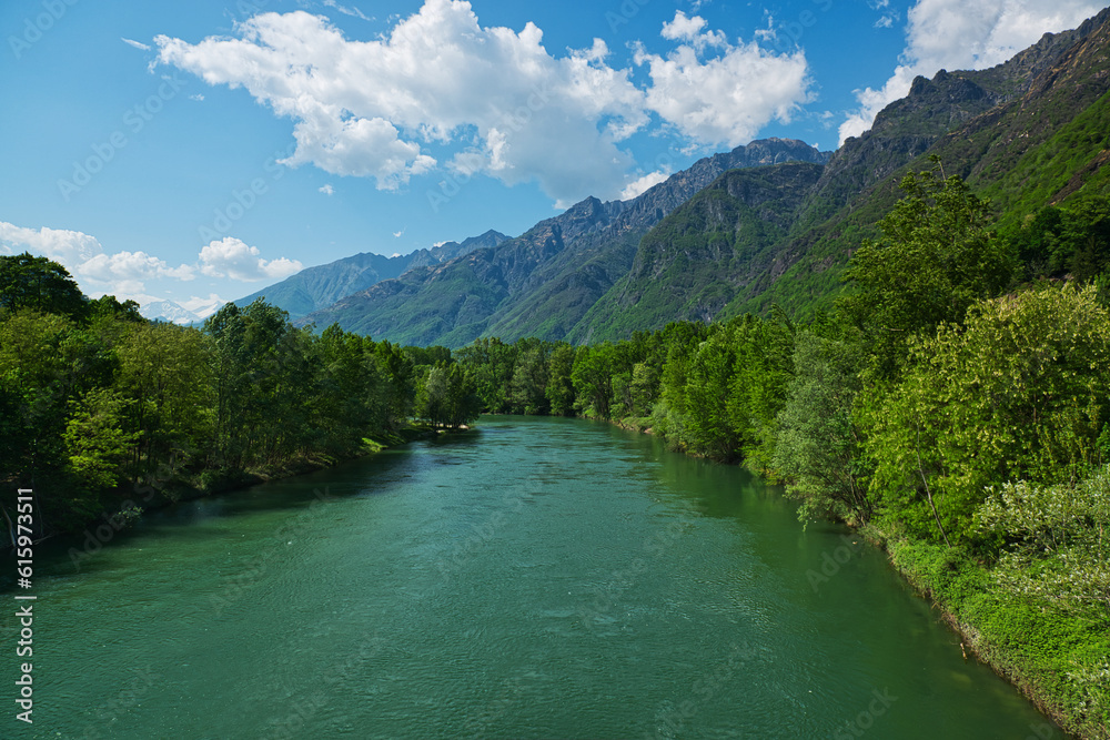 spring season on the river Toce with forest on the sides and mountains in the background and clouds in the sky