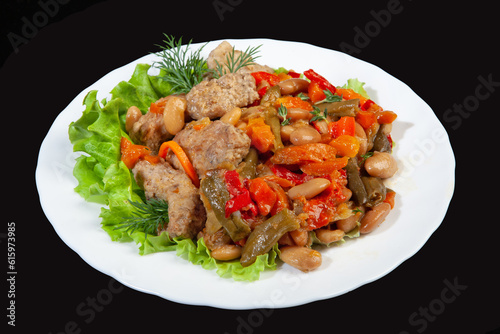 Porcelain plate with roasted meat and potatoes on a black studio background