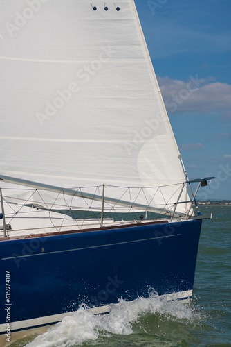 Close up of sailing boat, sail boat or yacht with a blue hull and white sails at sea