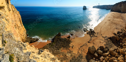 Summer evening Atlantic rocky coast view with sandy beach Praia dos Caneiros and lighthouse on cape (Lagoa, Algarve, Portugal). Two shots stitch panorama. photo